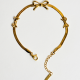 Gold bracelet with bow accents on a light gray background