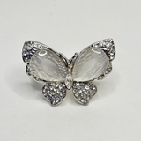 Butterfly-shaped ring with gemstones on a light gray background