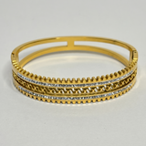 Gold bracelet with intricate design on a light gray background