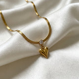 Gold necklace with a heart-shaped pendant on a white fabric background