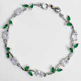 Silver bracelet with green and clear gemstones on a white background
