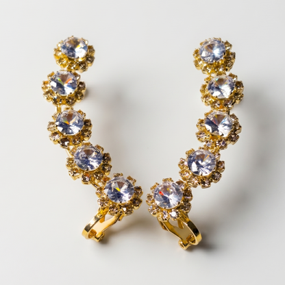 Gold earrings with clear gemstones on a light gray background