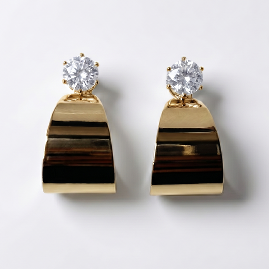 Gold earrings with clear gemstones on a light gray background