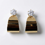 Gold earrings with clear gemstones on a light gray background