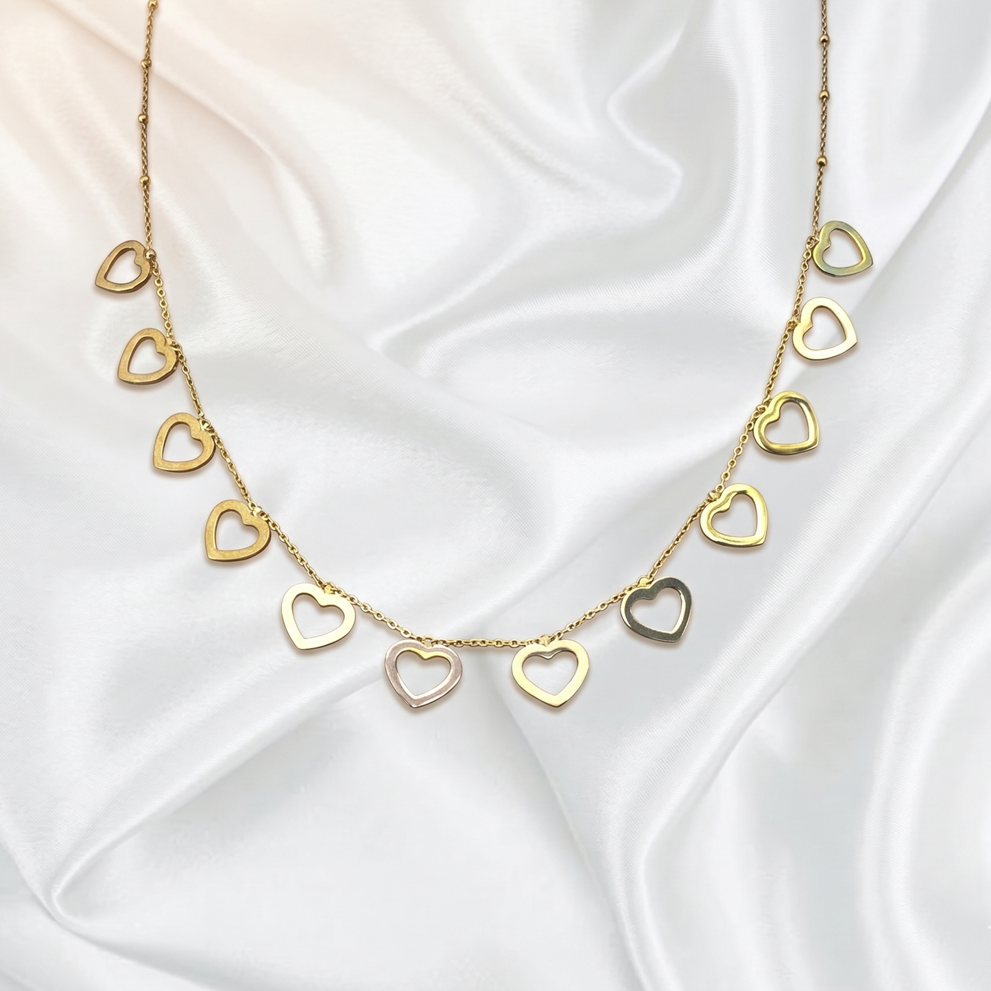 Gold heart-shaped necklace on a white satin background