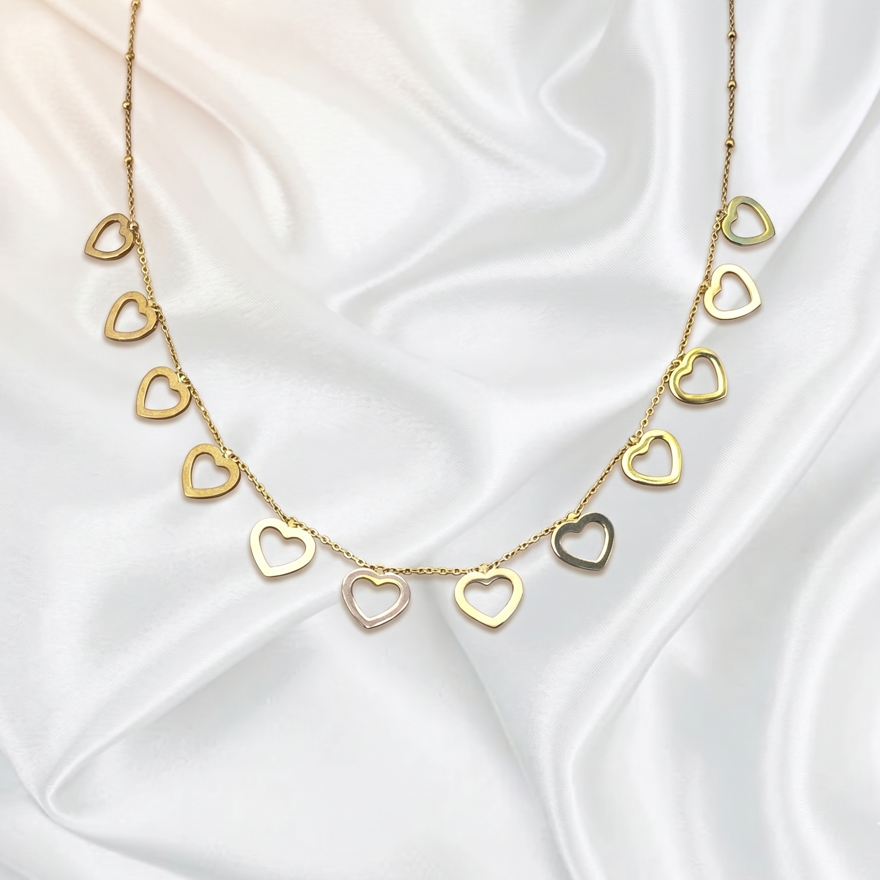 Gold heart-shaped necklace on a white satin background