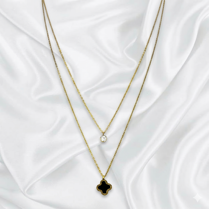 Two layer gold necklaces with clover pendants on a white fabric background