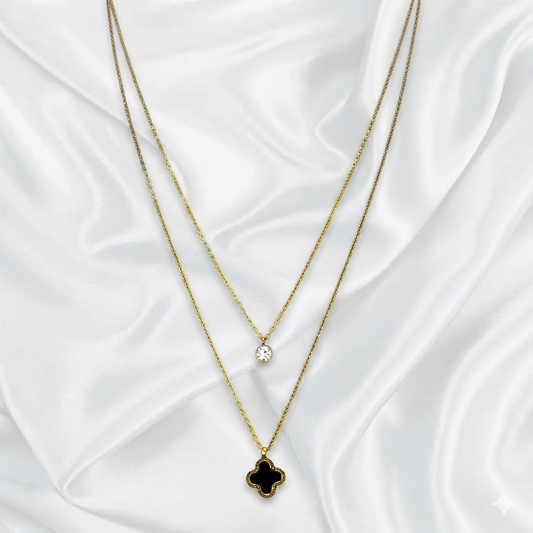 Two layer gold necklaces with clover pendants on a white fabric background