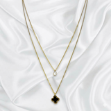Two layer gold necklaces with clover pendants on a white fabric background