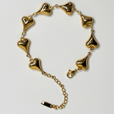 Gold bracelet with heart-shaped links on a light gray background