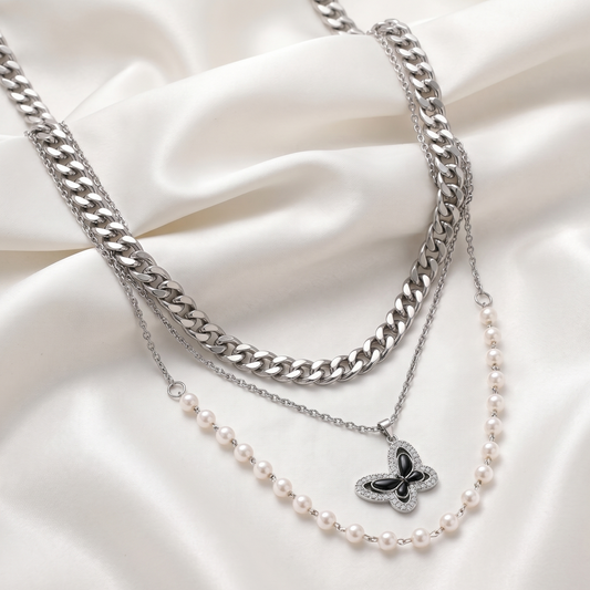 Necklaces with a butterfly pendant and pearl chain on a white fabric background