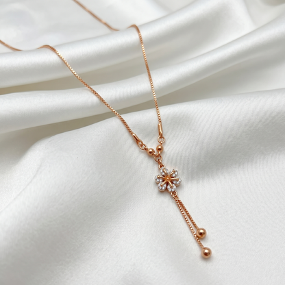 Rose gold necklace with a floral pendant on a white fabric background