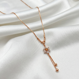 Rose gold necklace with a floral pendant on a white fabric background