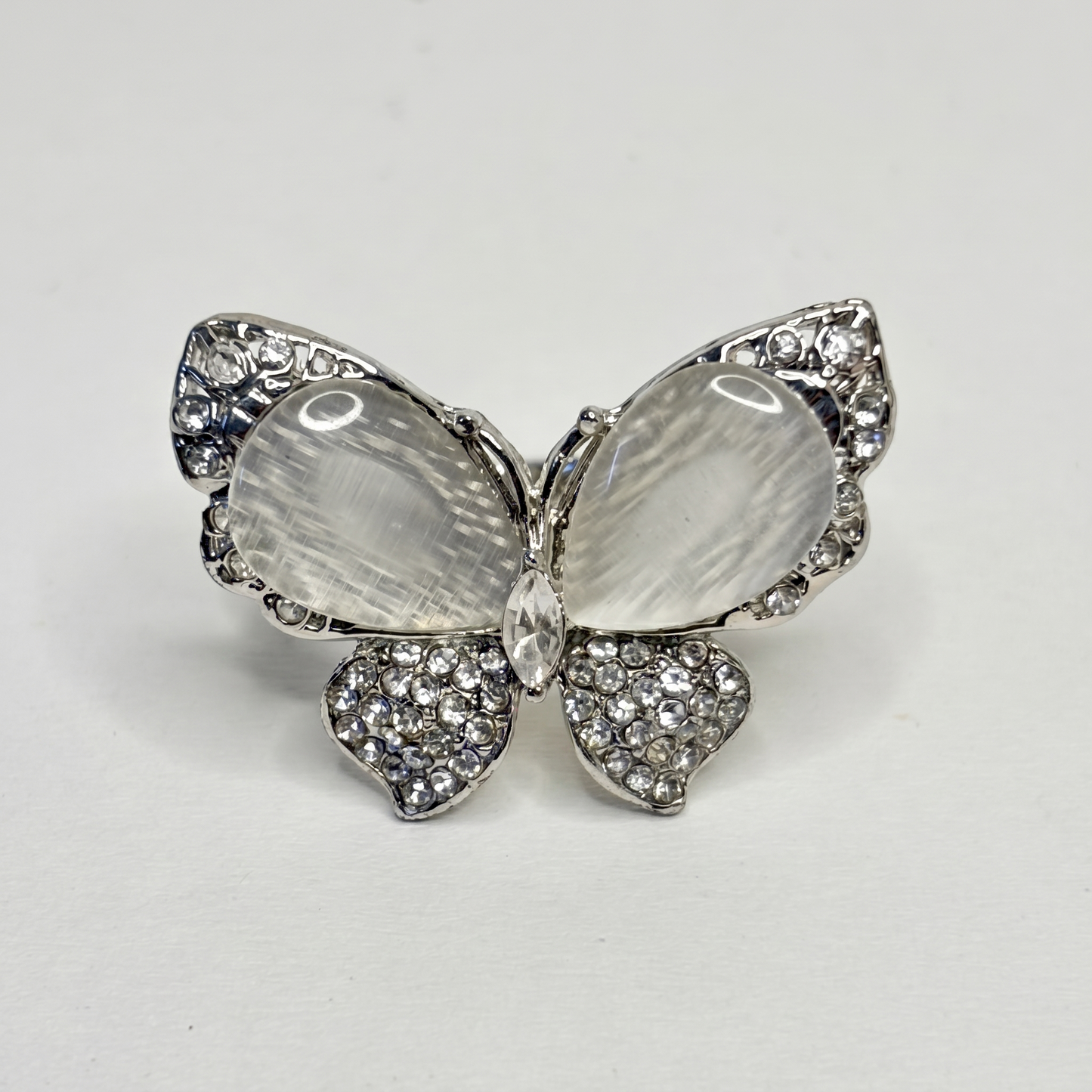 Butterfly-shaped ring with gemstones on a light gray background