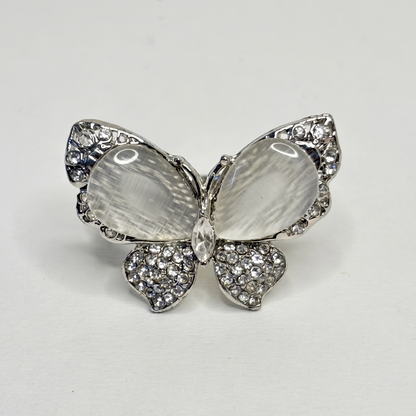 Butterfly-shaped ring with gemstones on a light gray background