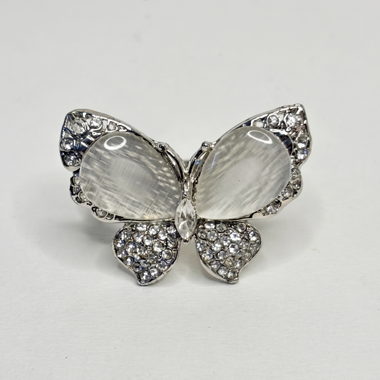 Butterfly-shaped ring with gemstones on a light gray background