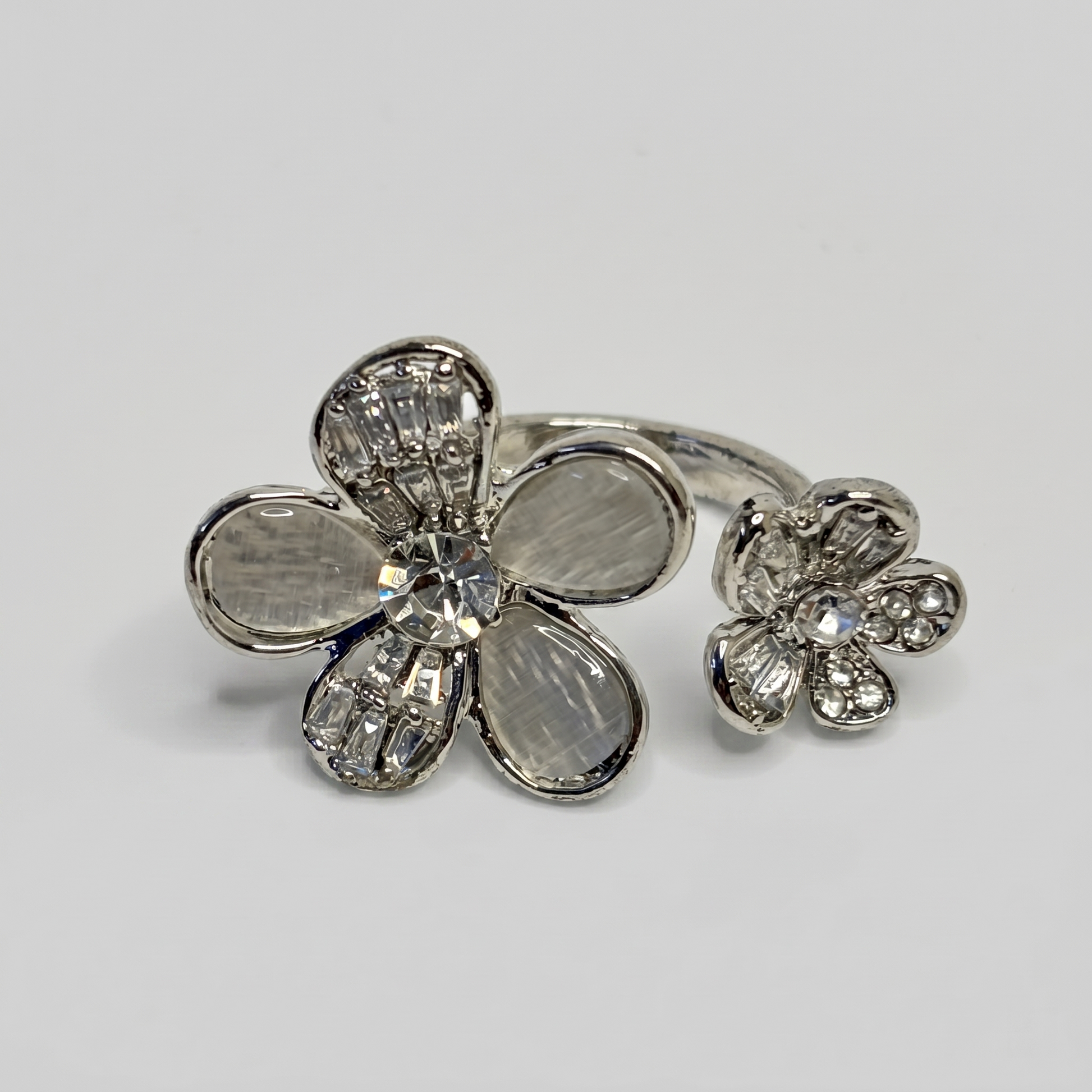 Silver flower-shaped ring with gemstones on a light gray background