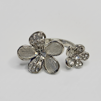 Silver flower-shaped ring with gemstones on a light gray background