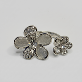 Silver flower-shaped ring with gemstones on a light gray background