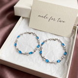 Pair of silver bracelets with blue stones in a box with a 'made for two' card.