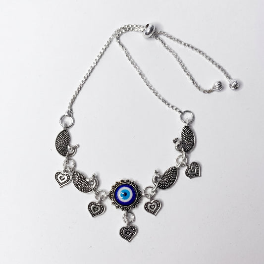 Silver ankletwith heart and eye-shaped charms on a white background