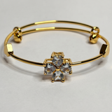 Gold bracelet with a decorative clasp featuring clear stones on a light gray background