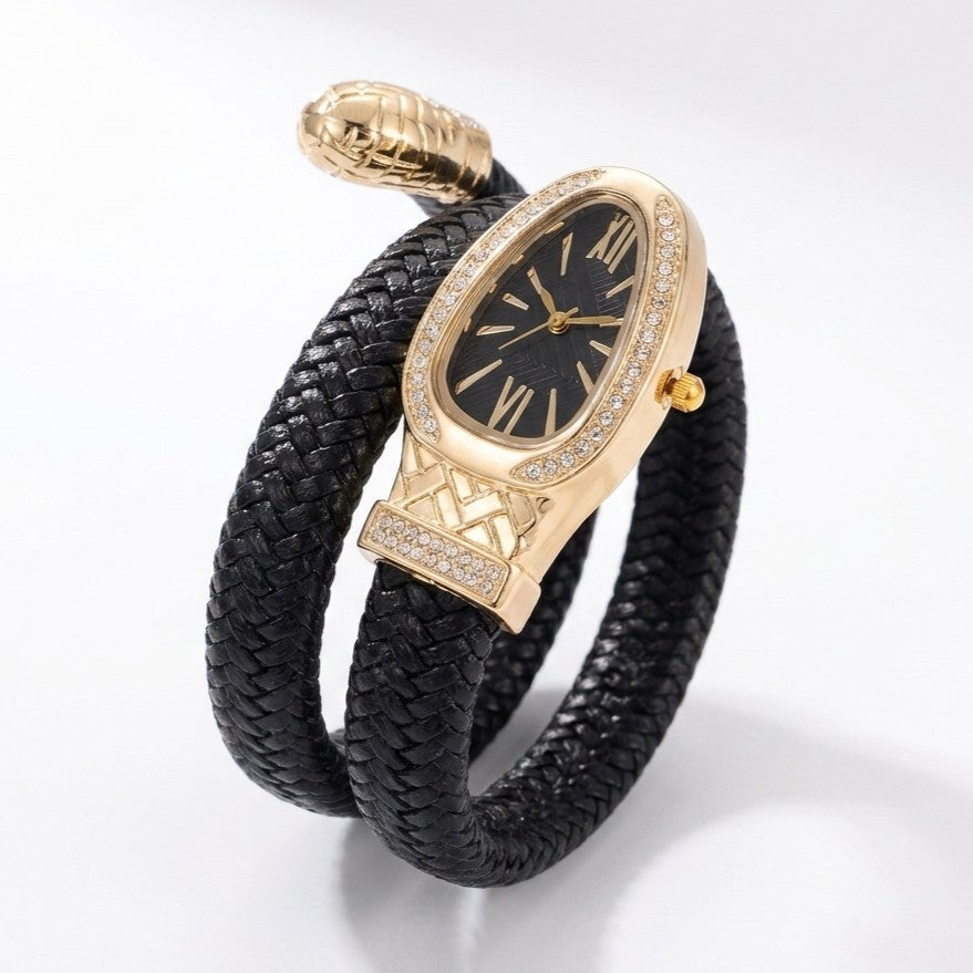 A luxury wrap-style watch featuring a black braided leather band, a gold-toned snake head buckle, a black dial with gold Roman numerals, and crystal accents around the bezel and crown.