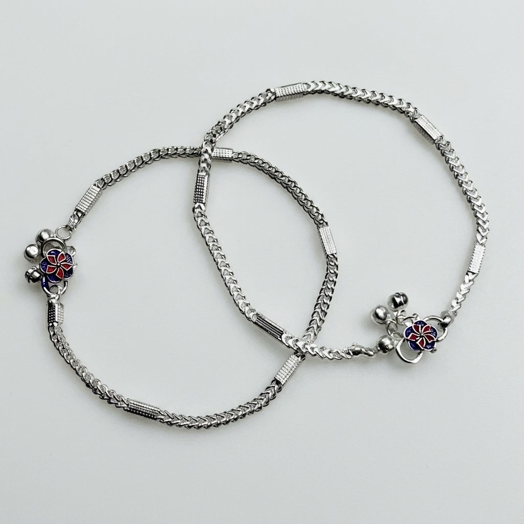 Two silver anklets with floral charms on a light gray background