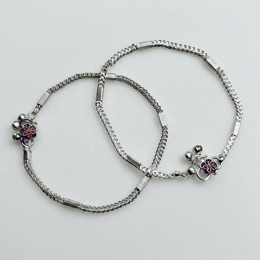 Two silver anklets with floral charms on a light gray background