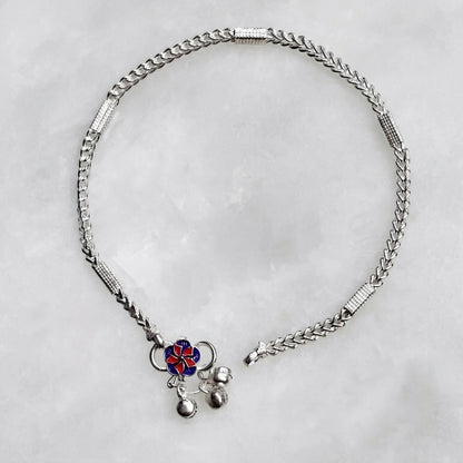 Silver anklet with a decorative pendant on a light gray background