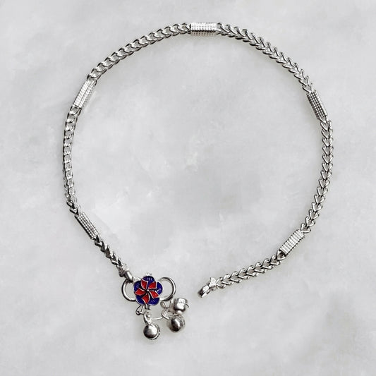 Silver anklet with a decorative pendant on a light gray background
