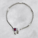 Silver anklet with a decorative pendant on a light gray background