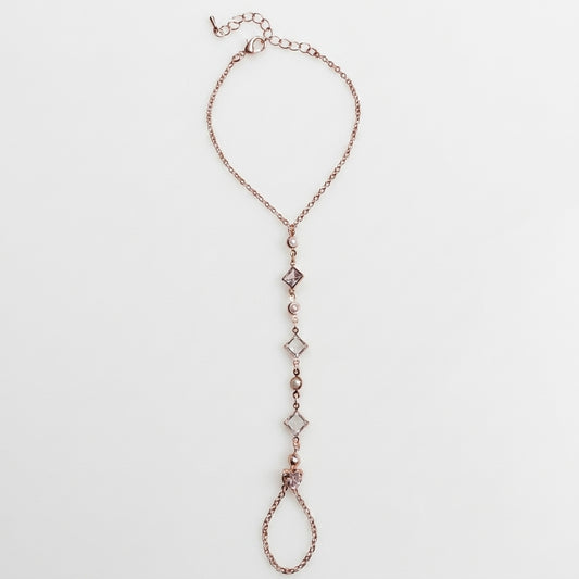 Rose gold hand chain with diamond-like beads on a light gray background