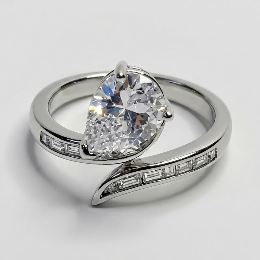 Silver ring with a pear-shaped diamond on a light gray background