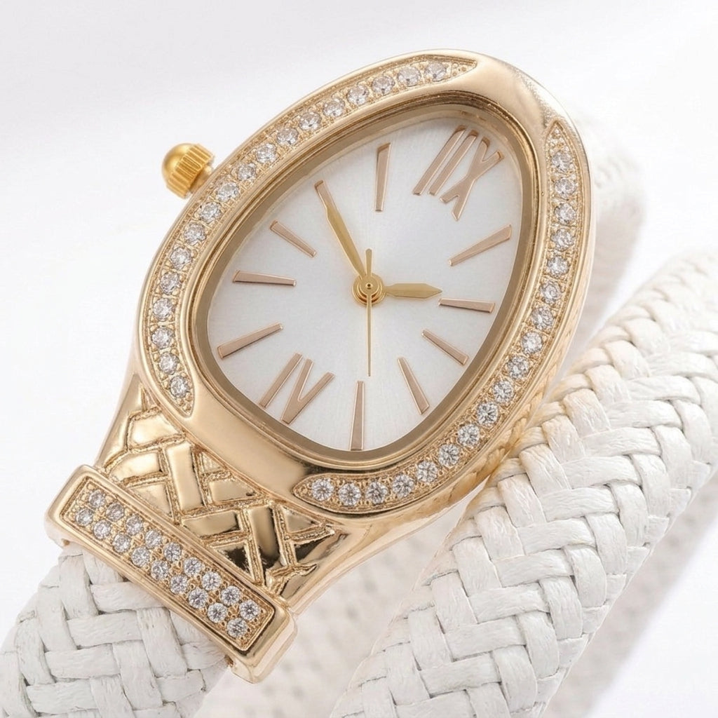 A luxury women's watch featuring a gold-tone oval case encrusted with clear crystals, a white dial with gold-tone Roman numerals, and a white braided leather strap.