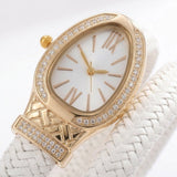A luxury women's watch featuring a gold-tone oval case encrusted with clear crystals, a white dial with gold-tone Roman numerals, and a white braided leather strap.
